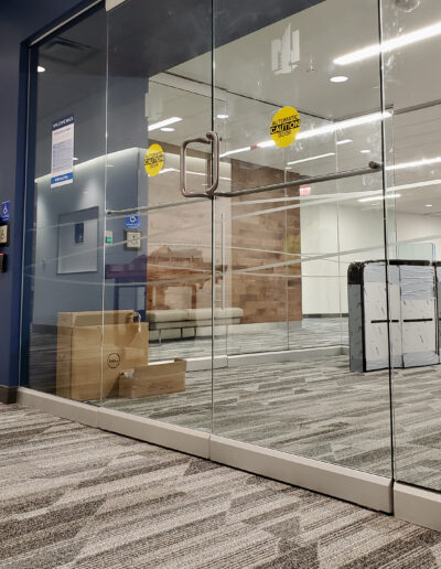 Double glass doors with caution automatic door stickers on both. An office entry is seen through the glass.